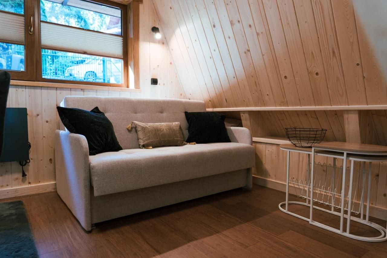Jasna sofa w domku z drewnianymi ścianami i oknem